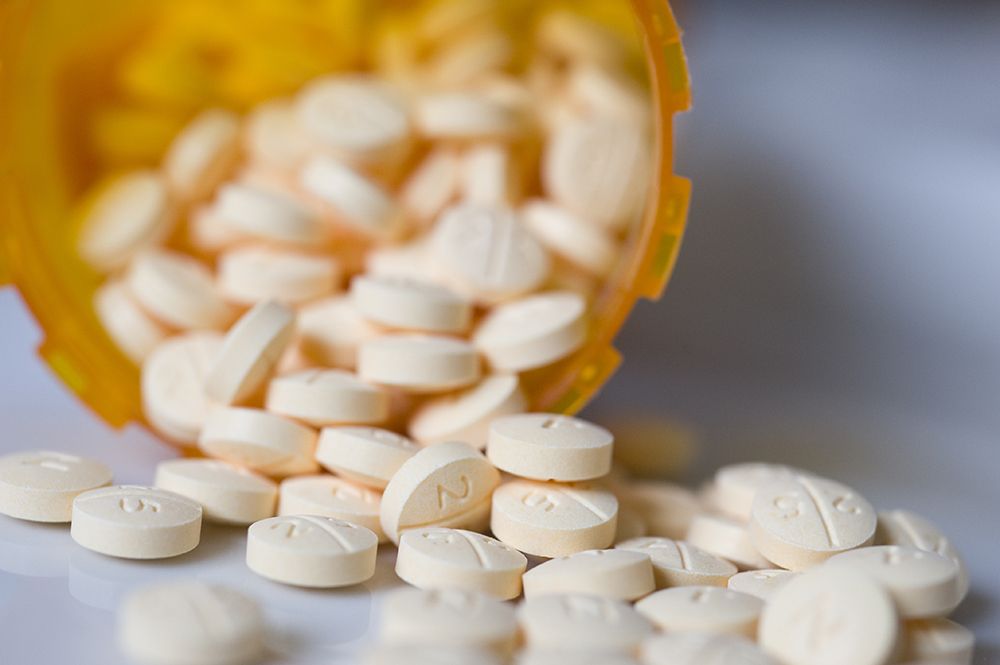 white pills spill from an orange prescription bottle