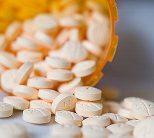 white pills spilling from an orange prescription bottle